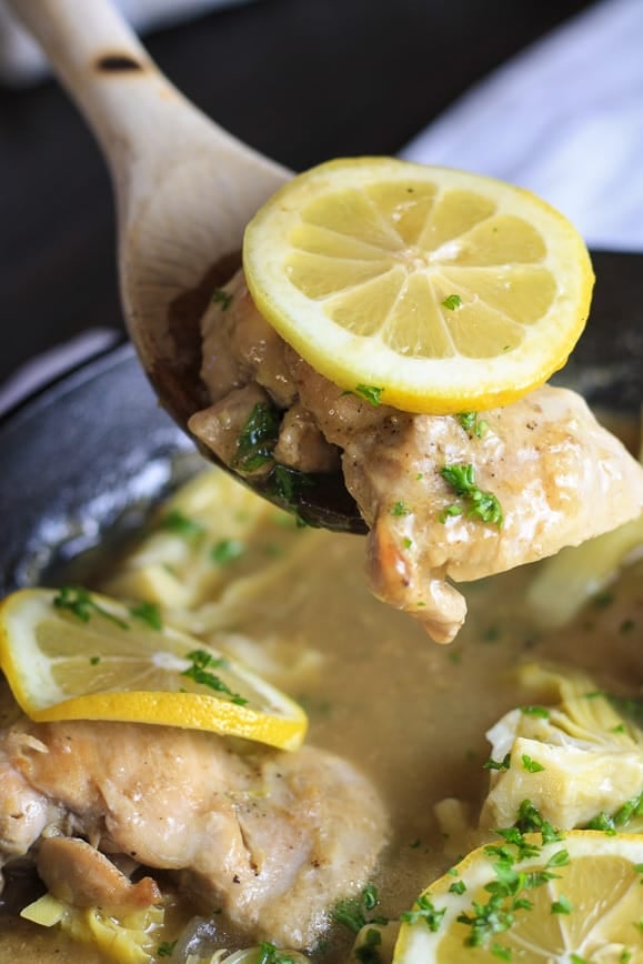 Chicken and lemon propped up on a wooden spatula spoon. 