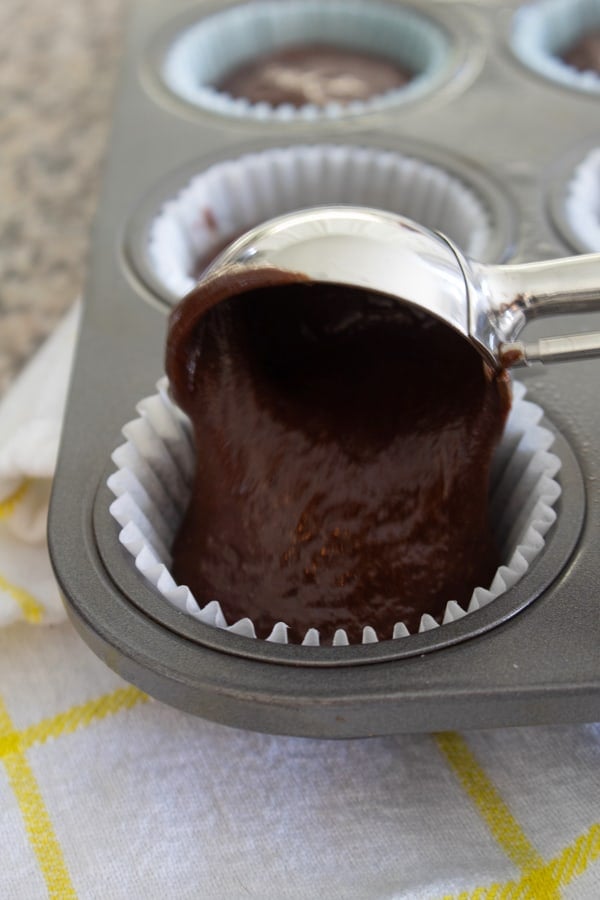 adding cupcake batter to pan with cookie scoop