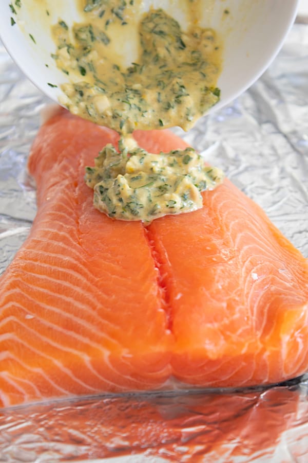 adding herb topping to salmon on sheet pan lined with foil