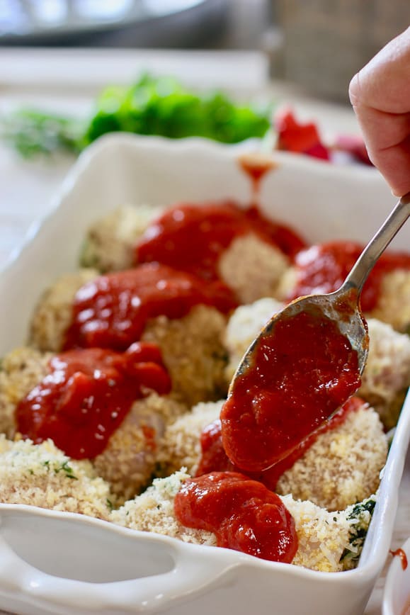 Toping chicken rollatini with a tablespoon of marinara