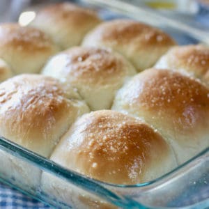 baked homemade rolls in a clear baking dish on top of a checkered napkin