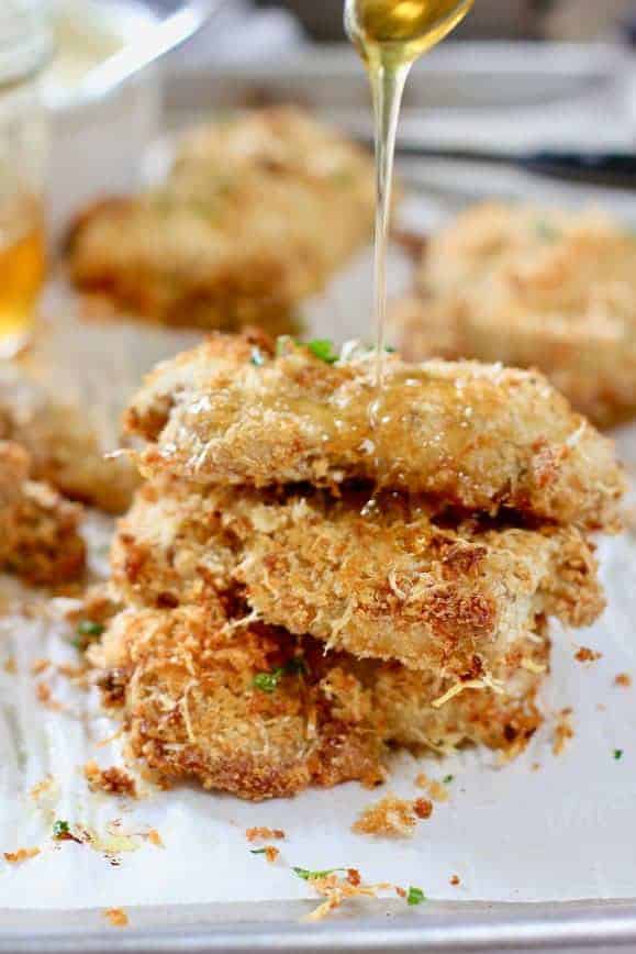 Crispy Chicken thighs being drizzled with a teaspoon of honey