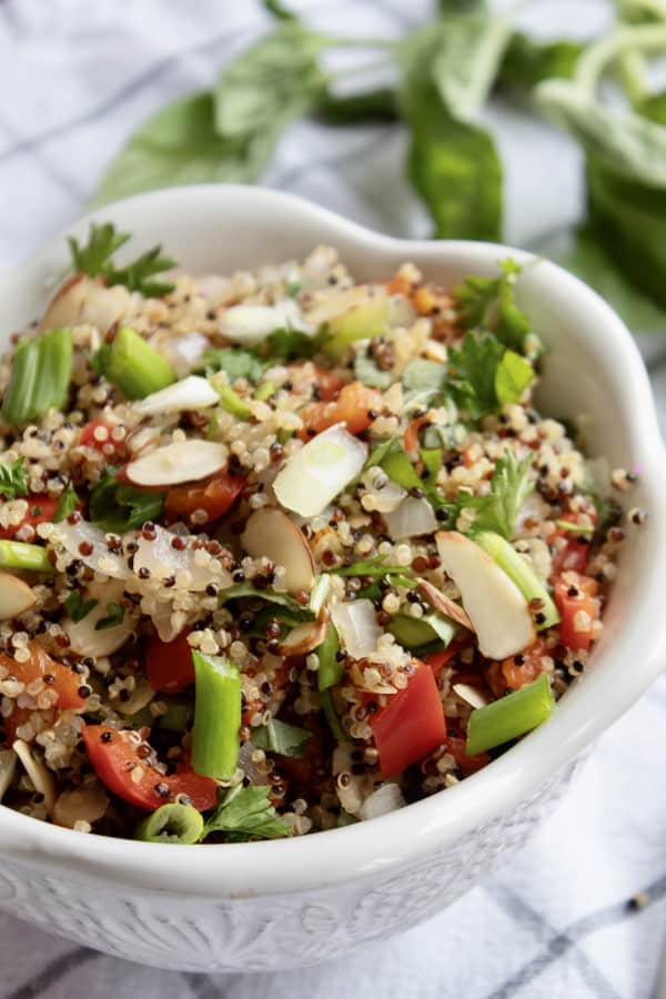 quinoa pilaf in white bowl with scallion garnish