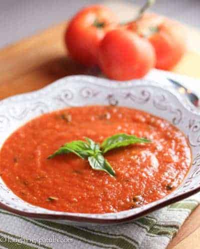 A big bowl of San Marzano Tomato soup with tomatoes in the background