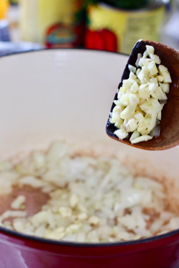 onion and garlic being cooked in a large pot