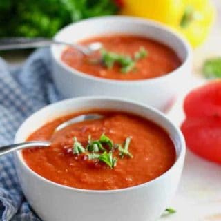 two bowls of tomato soup with spoons