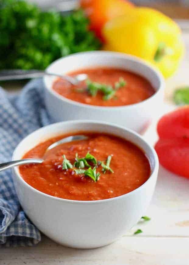 two bowls of tomato soup with spoons