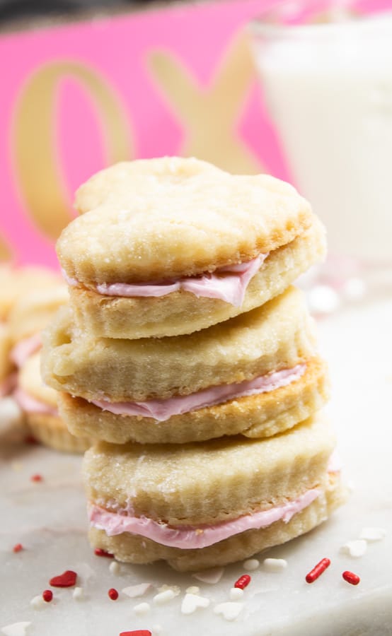 cream wafer cookies stacked with a pink background and red sprinkles on the surface