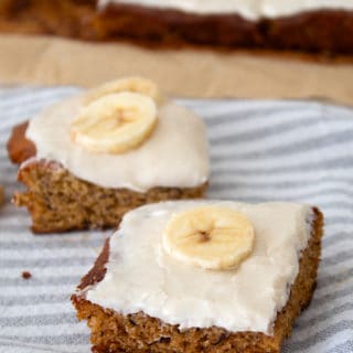 picture of banana bars on dish towel garnished with banana slices