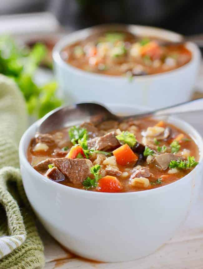Two white bowls of Beef Barley Soup
