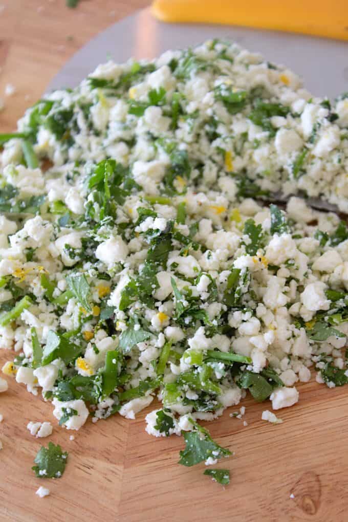 chopped herbs and feta on a cutting board