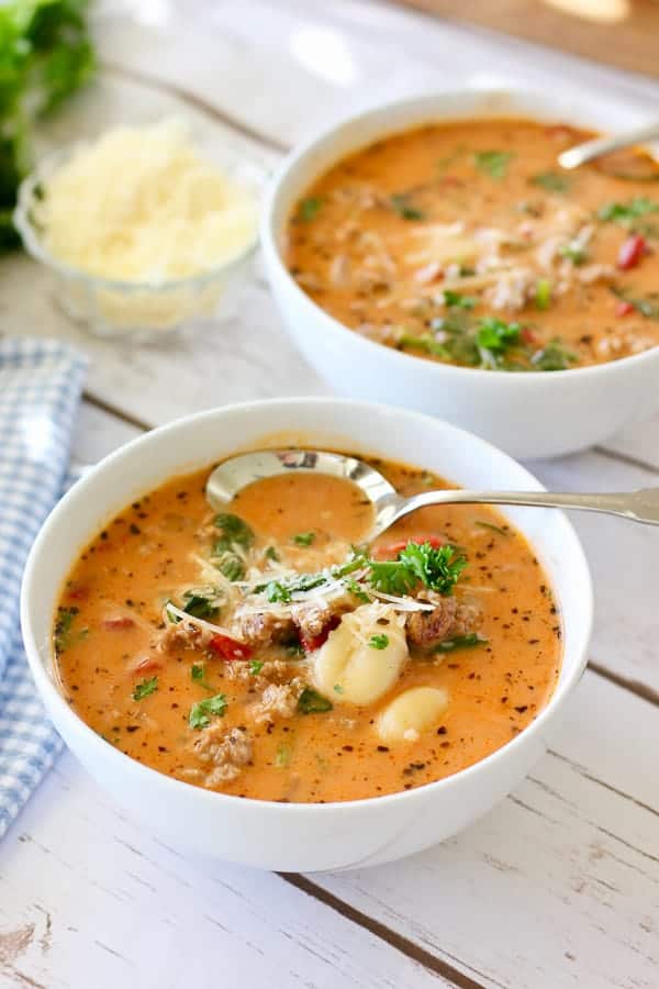  Zuppa di gnocchi di salsiccia in ciotole bianche con cucchiai