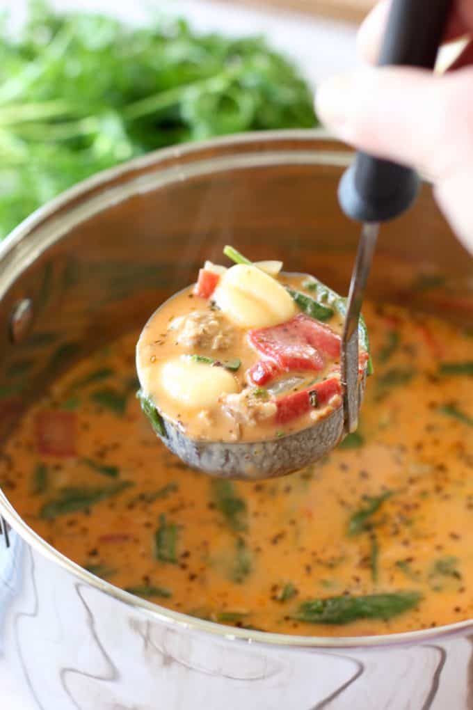 Gnocchi Sausage Soup in a ladle over a pot of soup