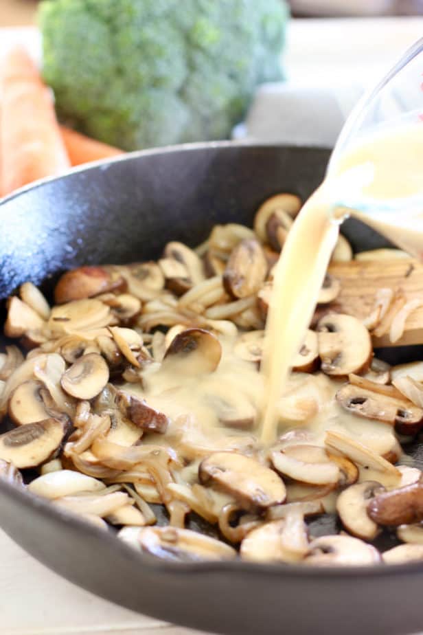 pouring stock and flour into mushrooms to make gravy