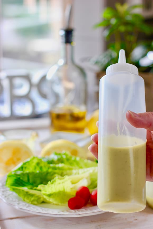 A chef squeeze bottle full of Lemon Dijon Vinaigrette