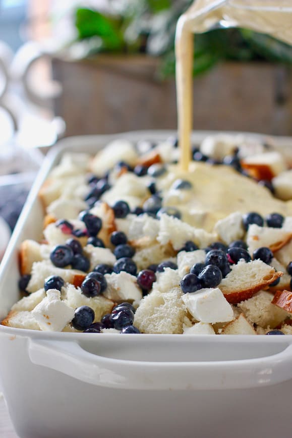 Pouring egg custard over the blueberry casserole