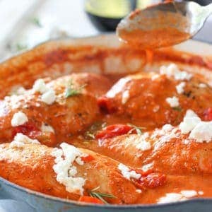 Chicken cooking in red pepper sauce skillet