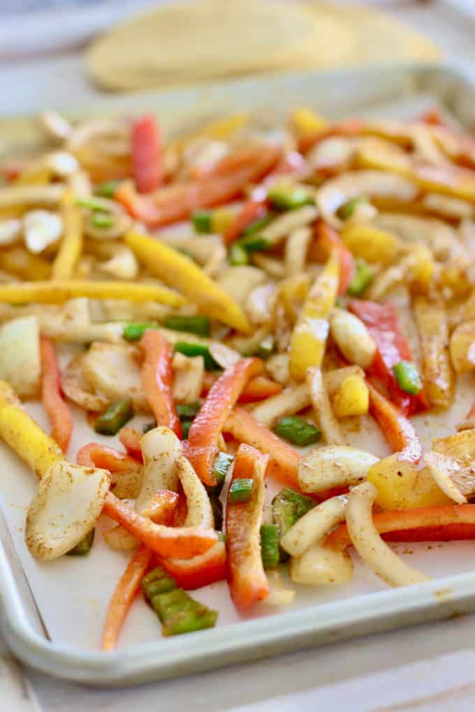 fresh cut bell peppers and onions on a sheet pan