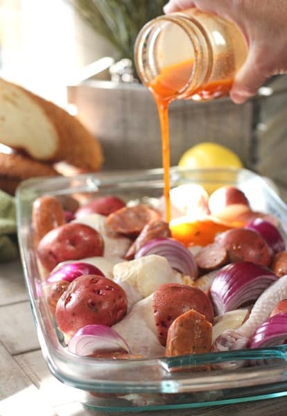 pouring marinade over chicken in glass pan