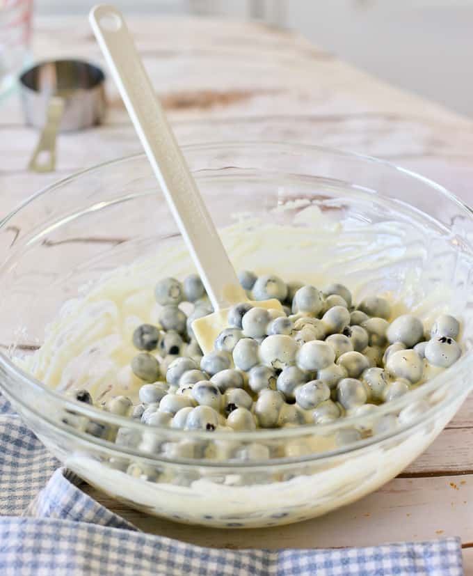 blueberries combined with batter in clear bowl