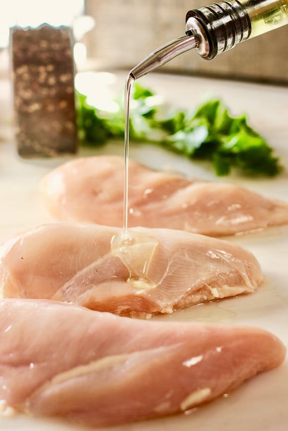 pouring olive oil over chicken breasts