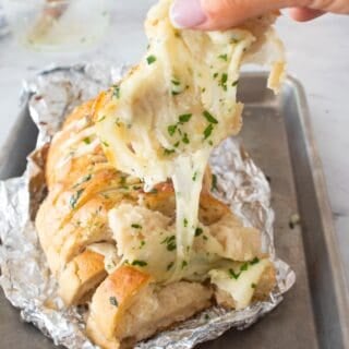 cheese pulling on a loaf of cheesy garlic bread