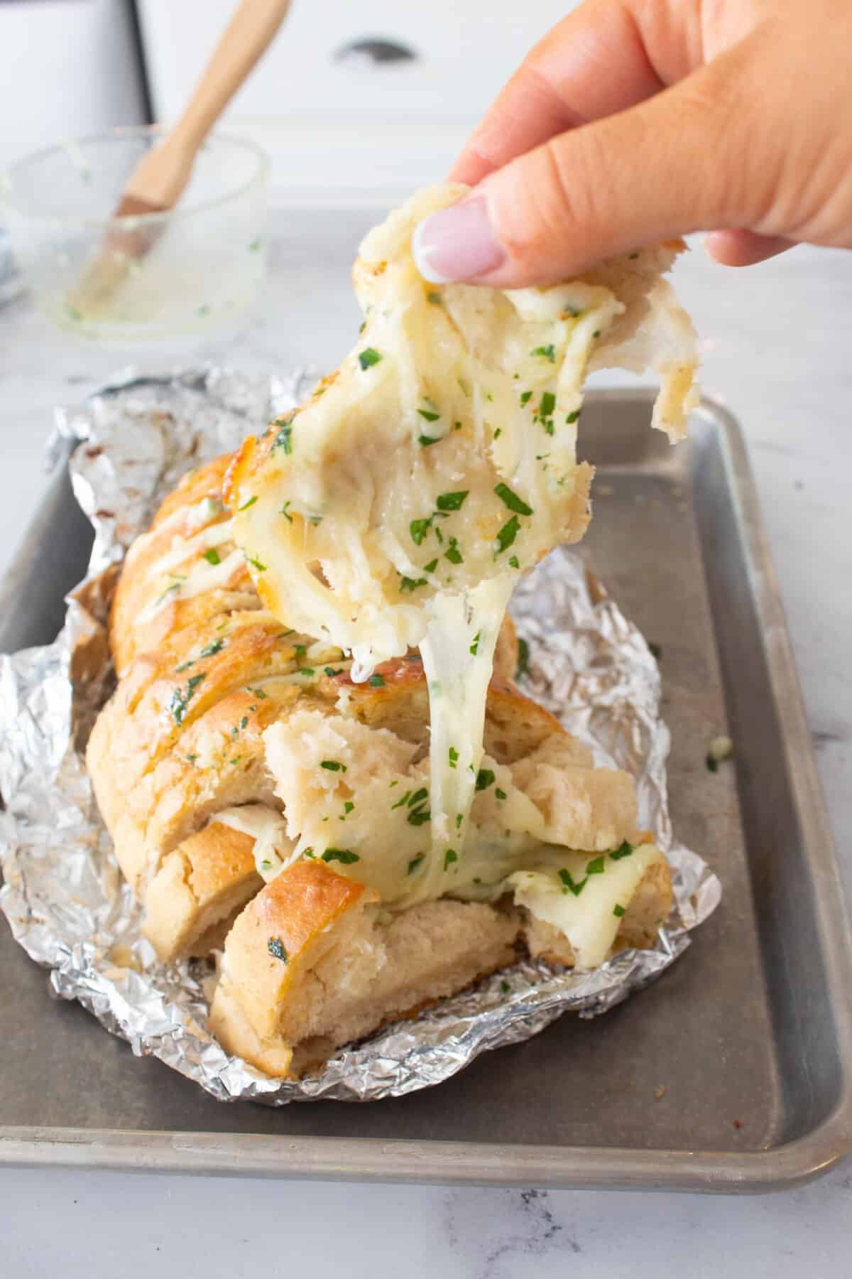 cheese pulling on a loaf of cheesy garlic bread