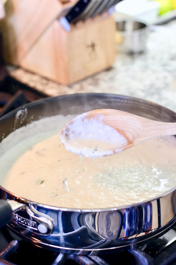 cream sauce with sage coating a wooden spoon