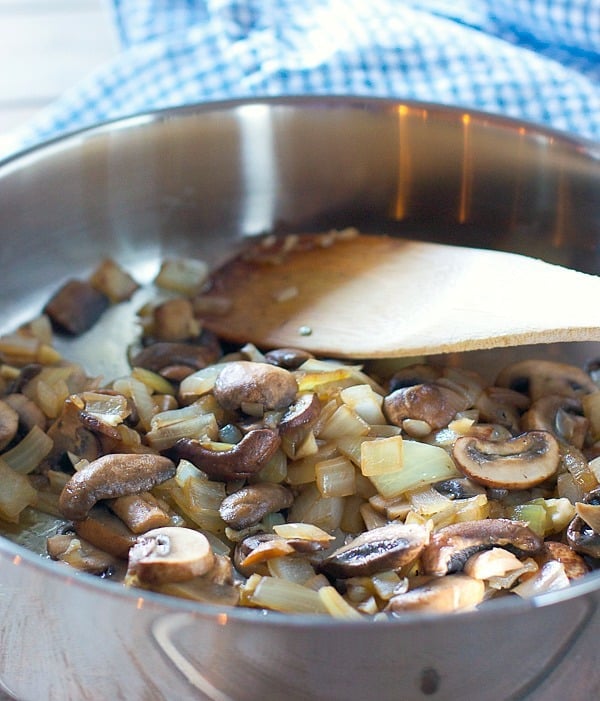 mushrooms and onions being cooked in a large skillet