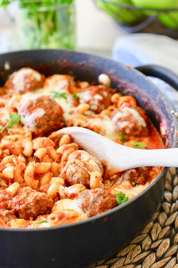 pasta and meatballs being served from skillet