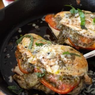tomato mozzarella and tomato stuffed chicken breasts in a cast iron skillet