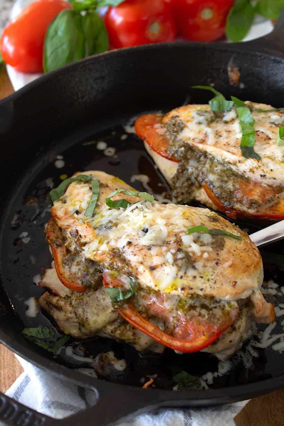 tomato mozzarella and tomato stuffed chicken breasts in a cast iron skillet