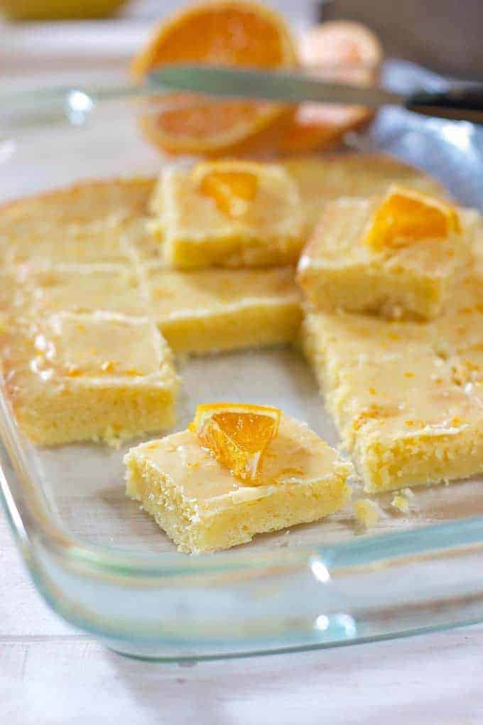 glazed orange bars in a clear pan garnished with orange wedges