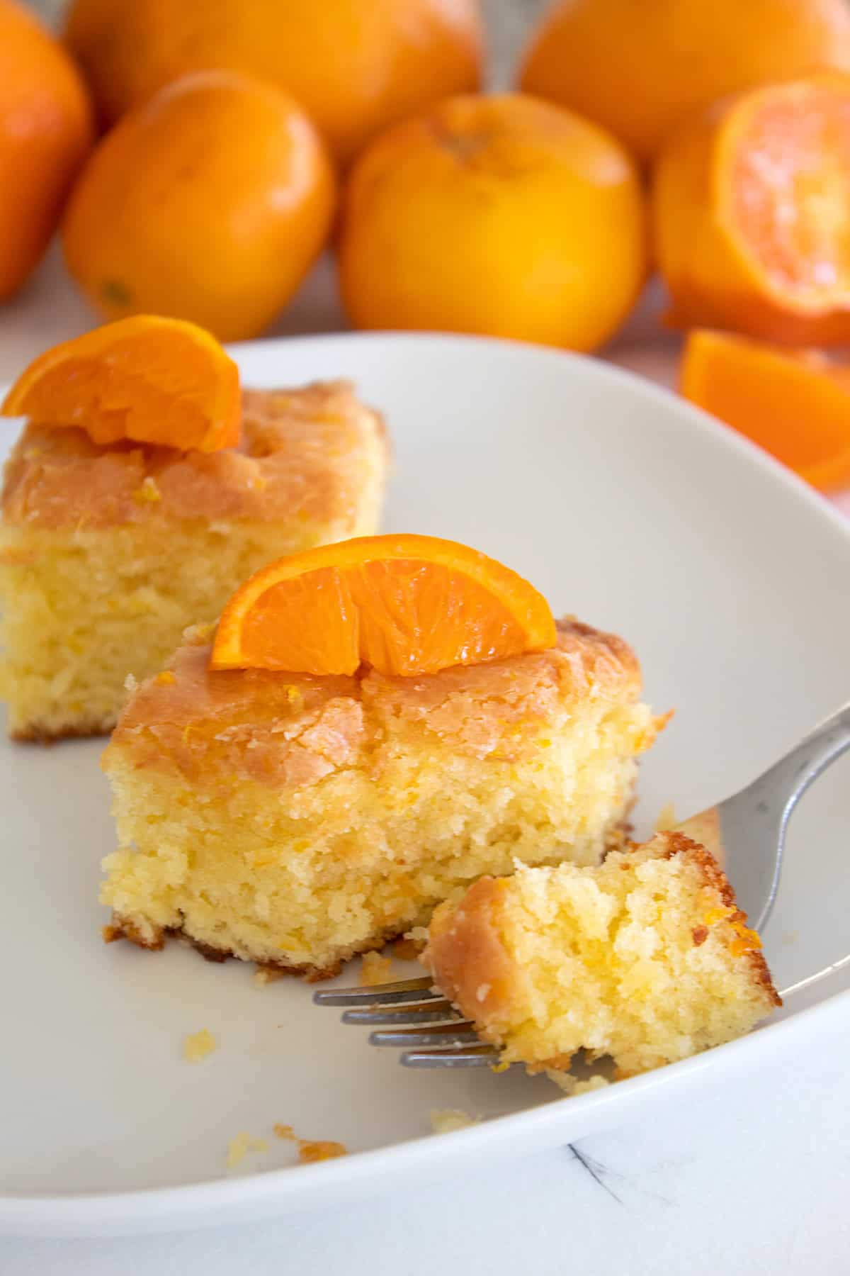 orange brownies on a white plate with tangerines in back ground