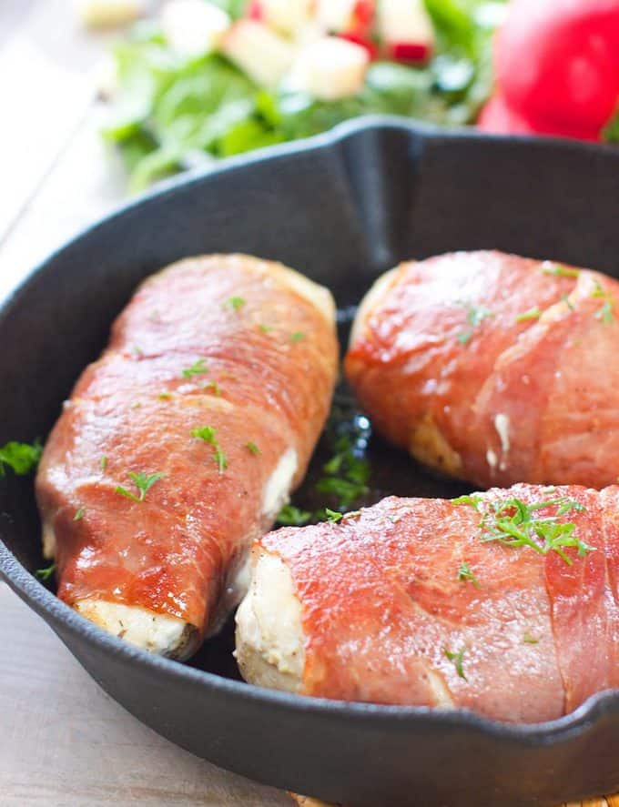 Seared chicken breasts wrapped in prosciutto in a cast iron skillet