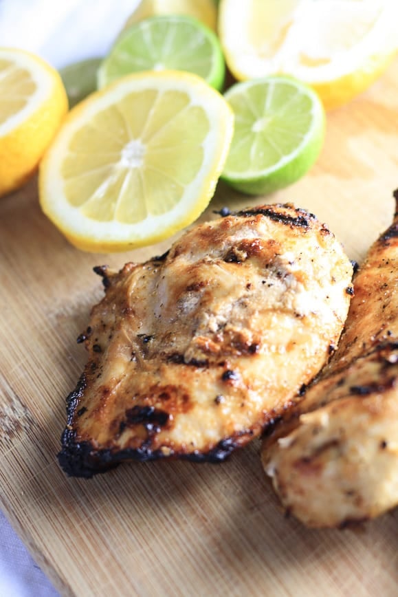 Lemon Grilled Chicken on a Cutting Board with Sliced Lemons and Limes