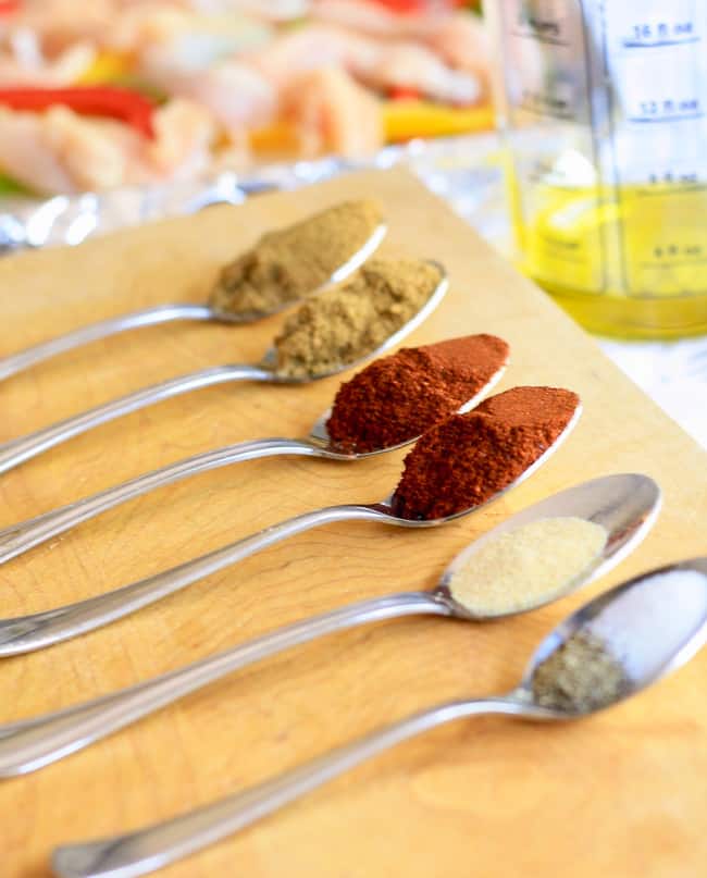 Spices proportioned on spoons to make fajita sauce to pour over chicken