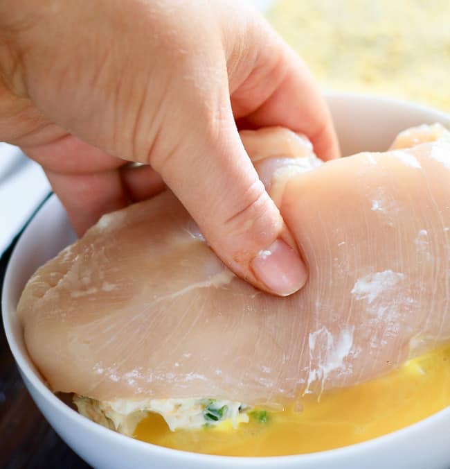 Dipping stuffed chicken breast into egg mixture.