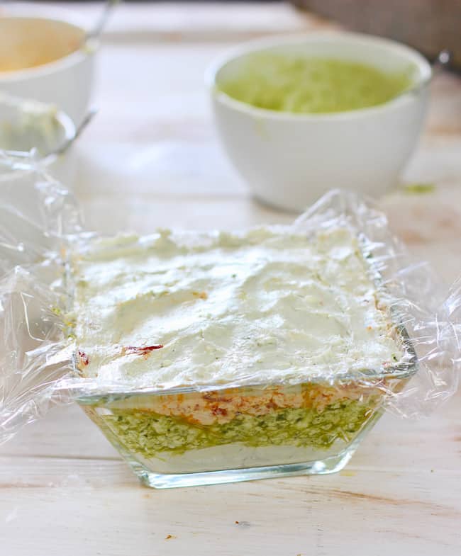 A 3 layer dip in a clear dish with cellophane