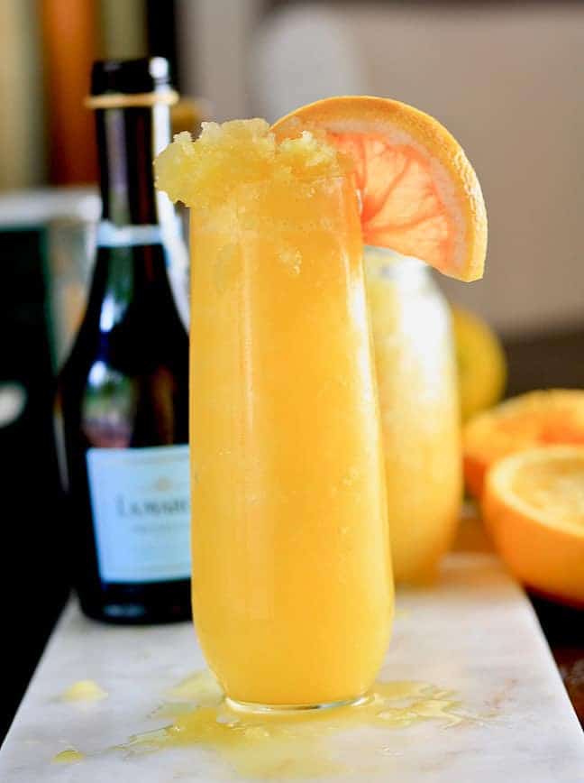 Frozen Mimosa Cocktail on a white cutting board garnished with a grapefruit wedge.