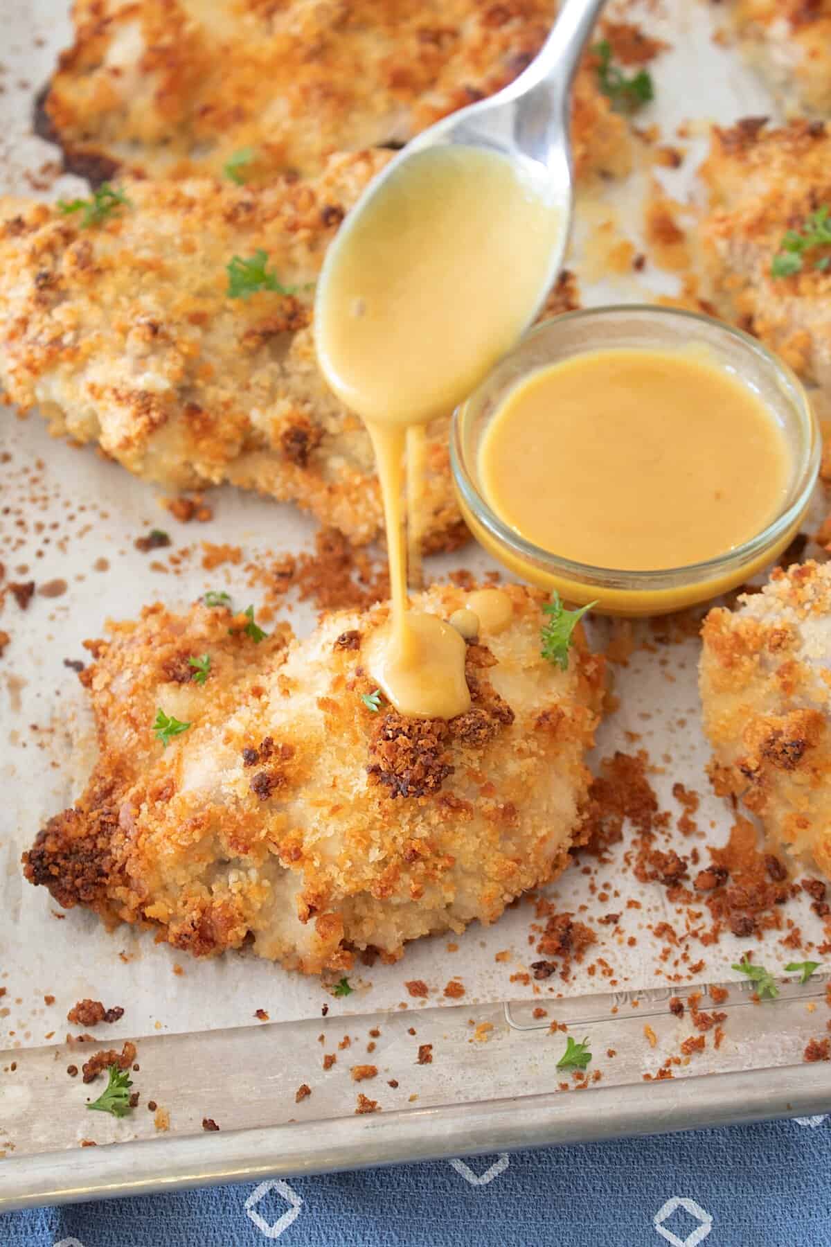 drizzling honey mustard onto crispy chicken thigh