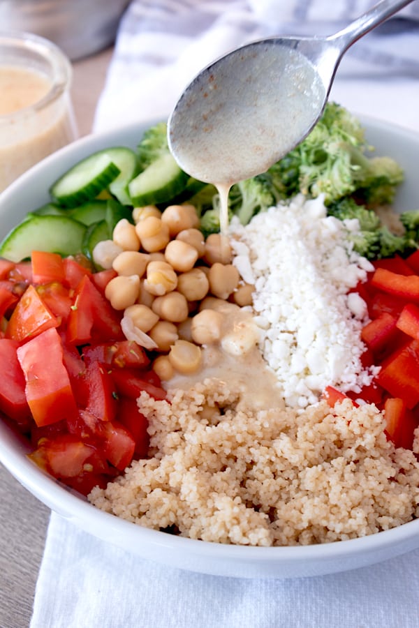 adding lemon vinaigrette to couscous salad