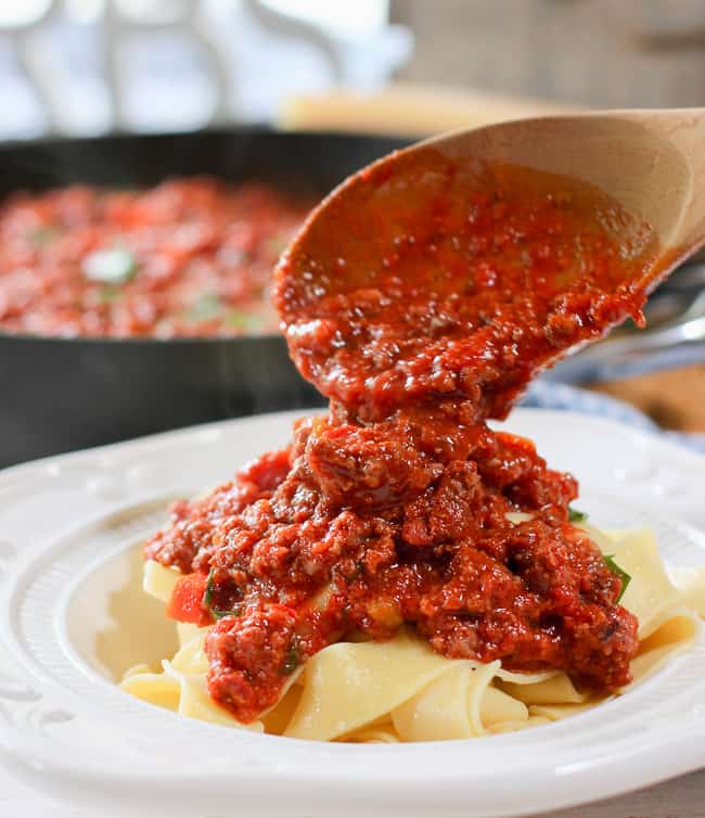 Classic Bolognese sauce being poured on pasta