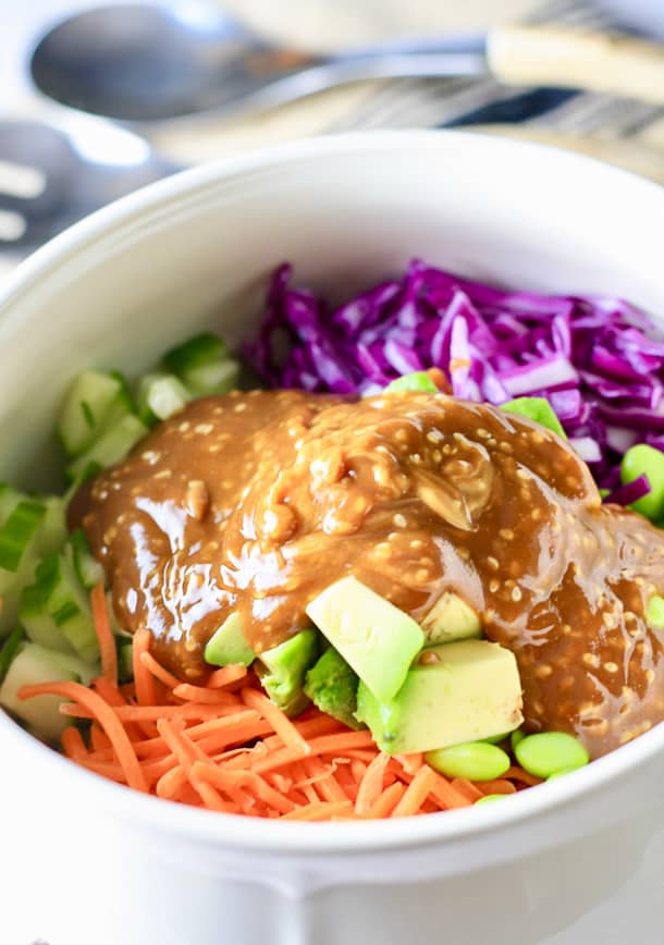 A white bowl filled with soba noodle salad with dressing poured on top