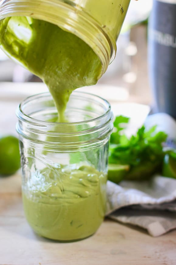 a mason jar with avocado lime sauce being poured into it