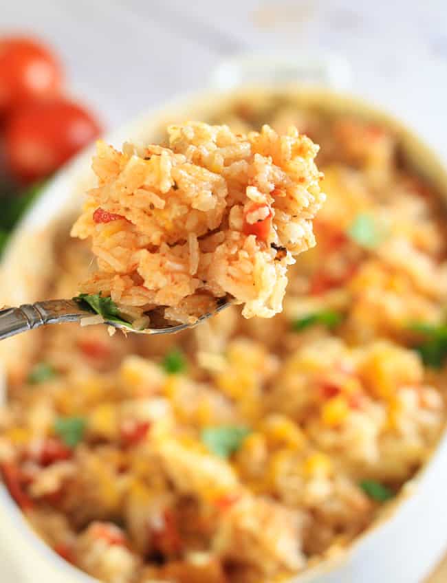 A White Pan of Mexican Rice with a Portion on a fork held above a casserole dish