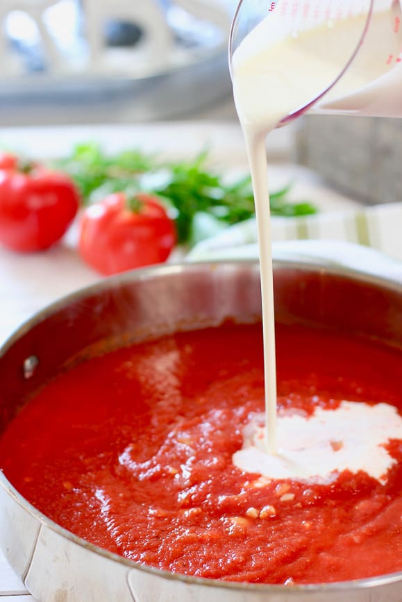 cream being poured into tomato puree