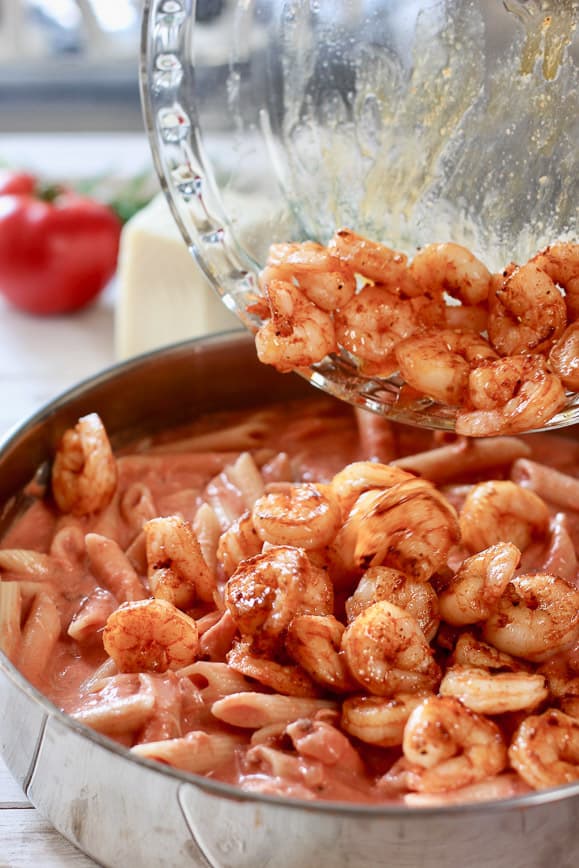 shrimp being added to pasta and cream sauce