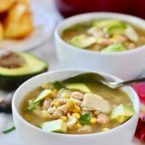 two bowls of white chicken chili with a spoon