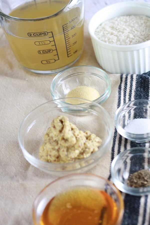 Clear small dishes with ingredients for broth mixture including dijon mustard, honey, salt, pepper, powdered garlic and chicken broth in a mis en place setting